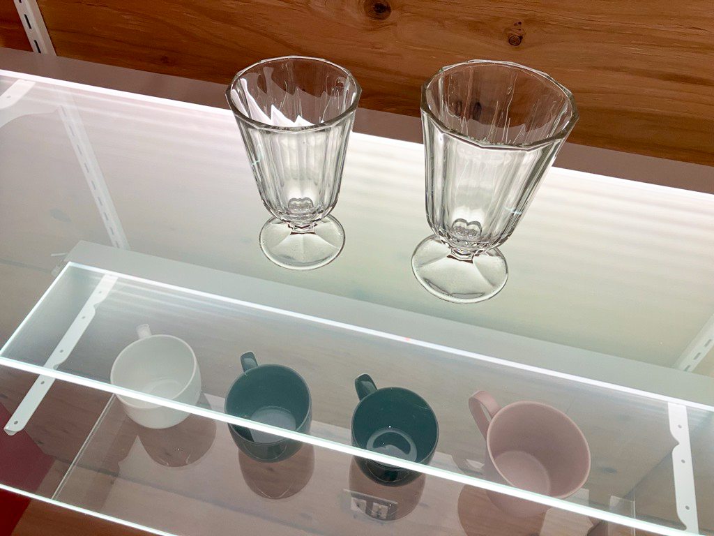 RAYCREAを活用した商品棚にガラス製品のコップ、マグカップを設置した様子。棚板は商品を明るく照らしながら、棚板は透明性を維持するため、商品の見やすさが期待される。